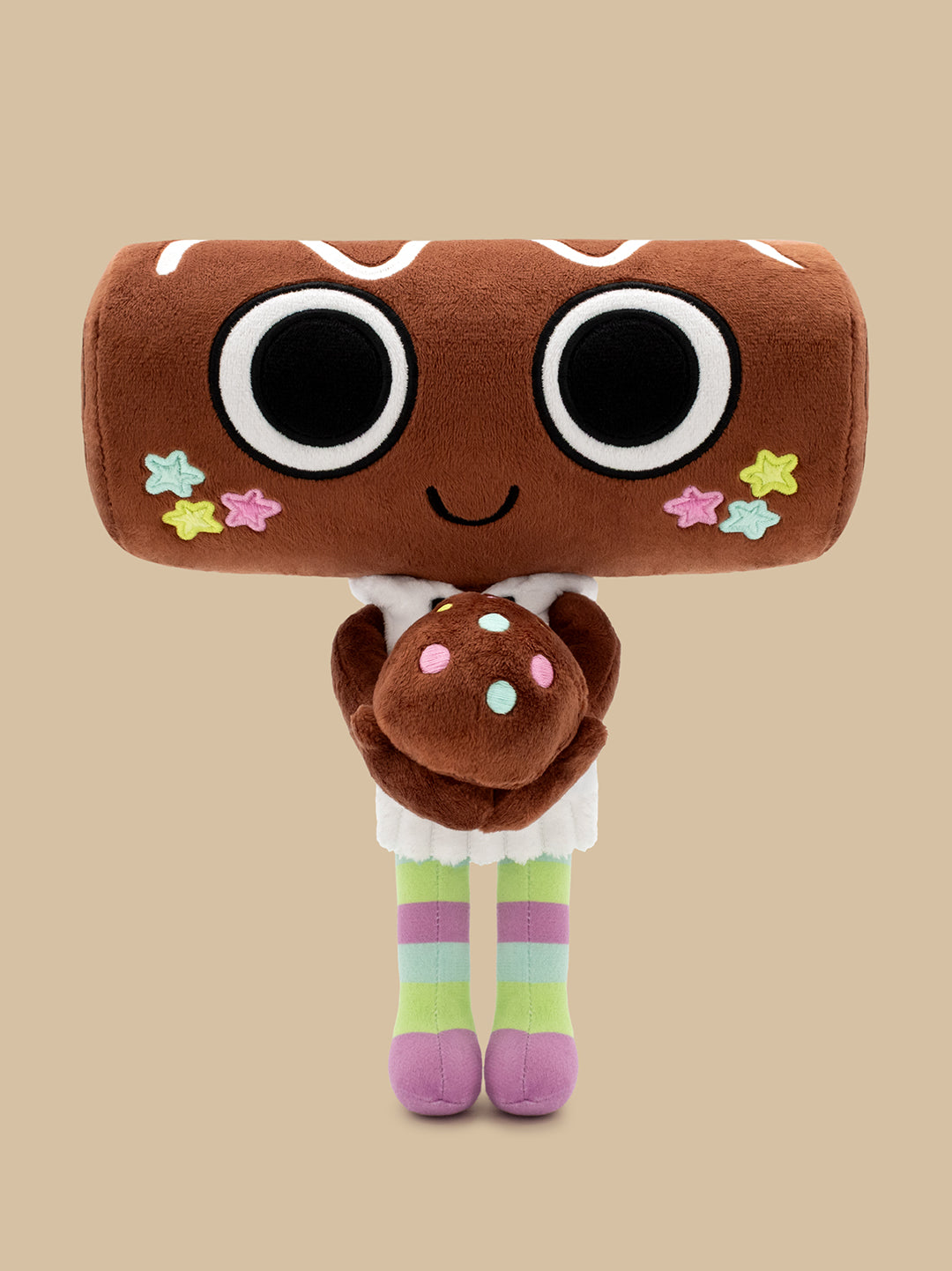 A plush toy shaped like a brown donut or cookie with oversized black-and-white eyes, a small smile, pastel star accents, and striped pastel legs, standing against a plain beige background.