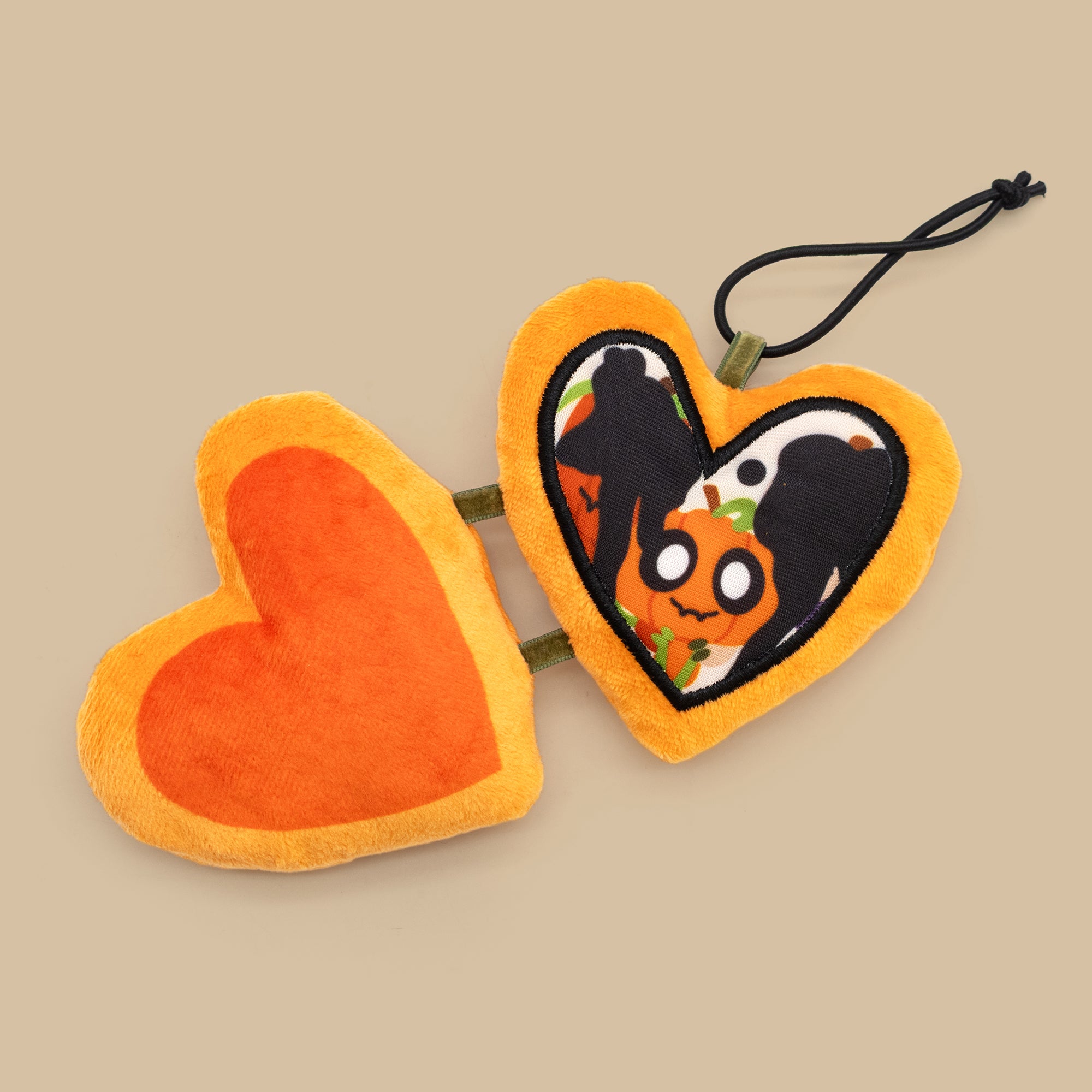 Heart-shaped Halloween-themed plush toy with a black silhouette of a person on a pumpkin.