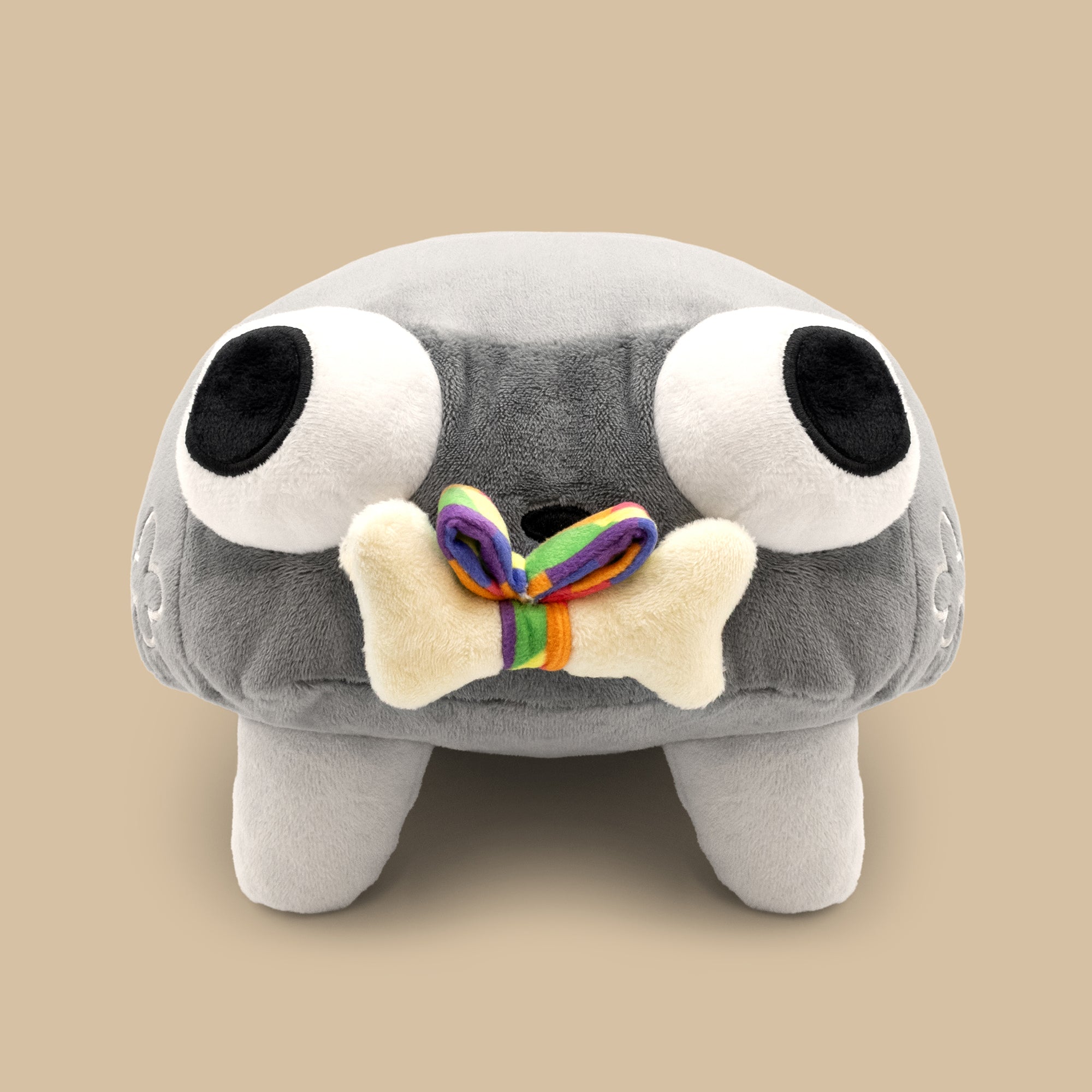 Gray plush toy with large eyes and a rainbow bone on a beige background