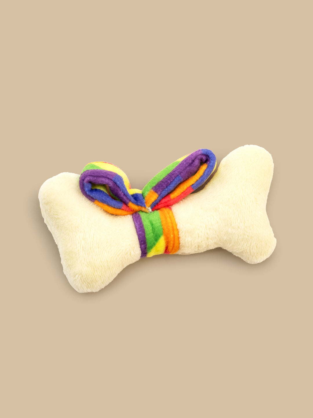 Bone-shaped toy with rainbow bow on a beige background