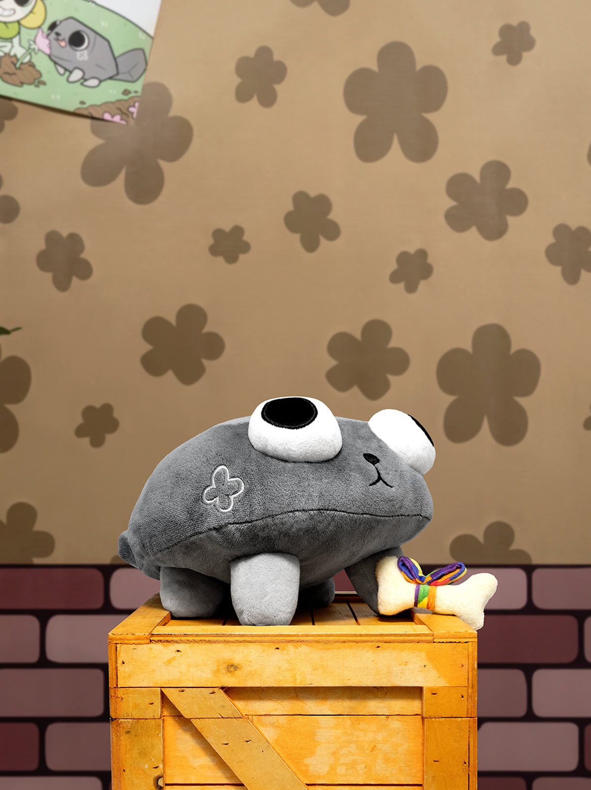 Gray plush toy with a white face on a wooden crate against a patterned wall.
