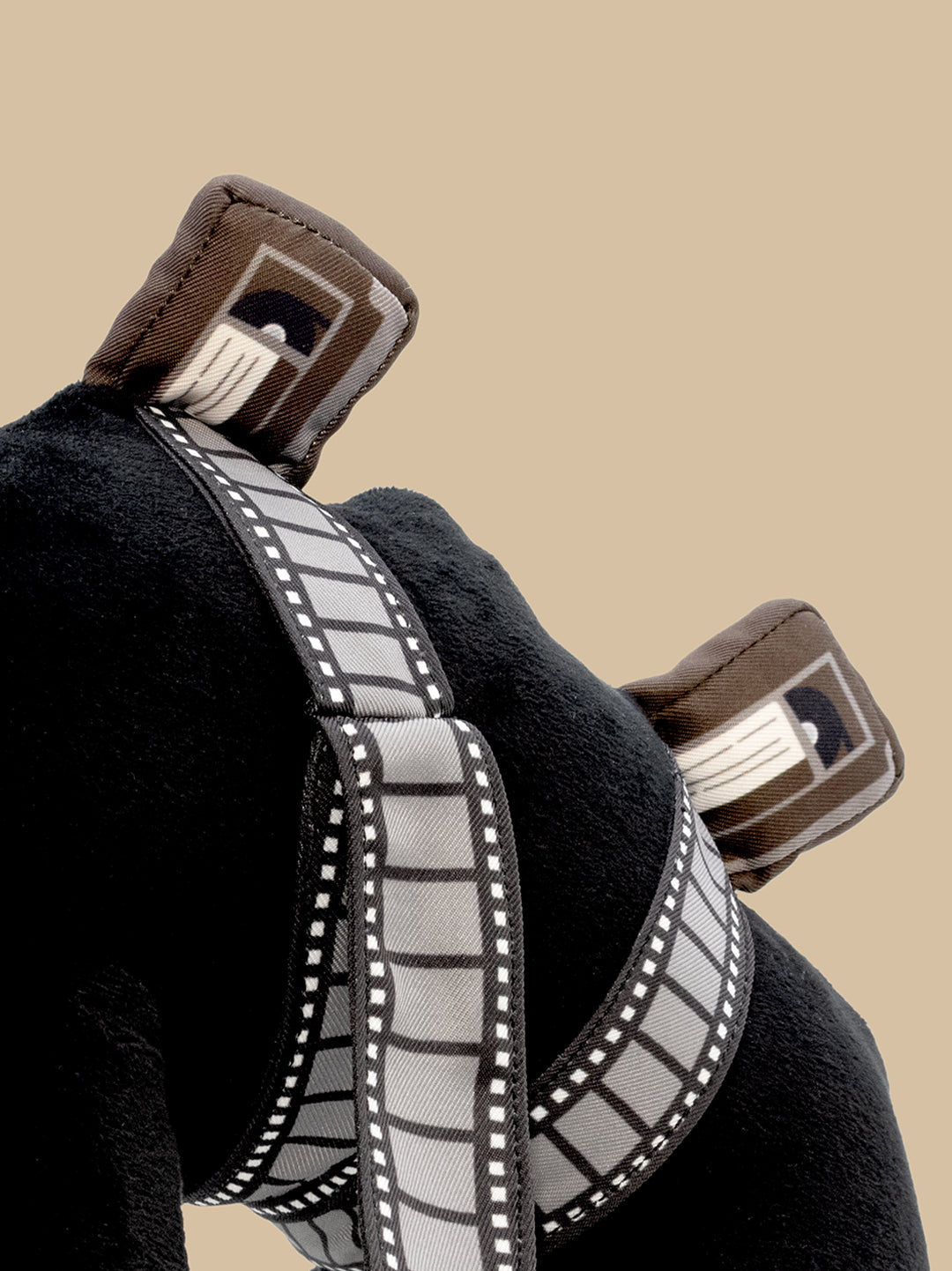 Close-up of plush with a gray and white tape reel and tapes on a beige background