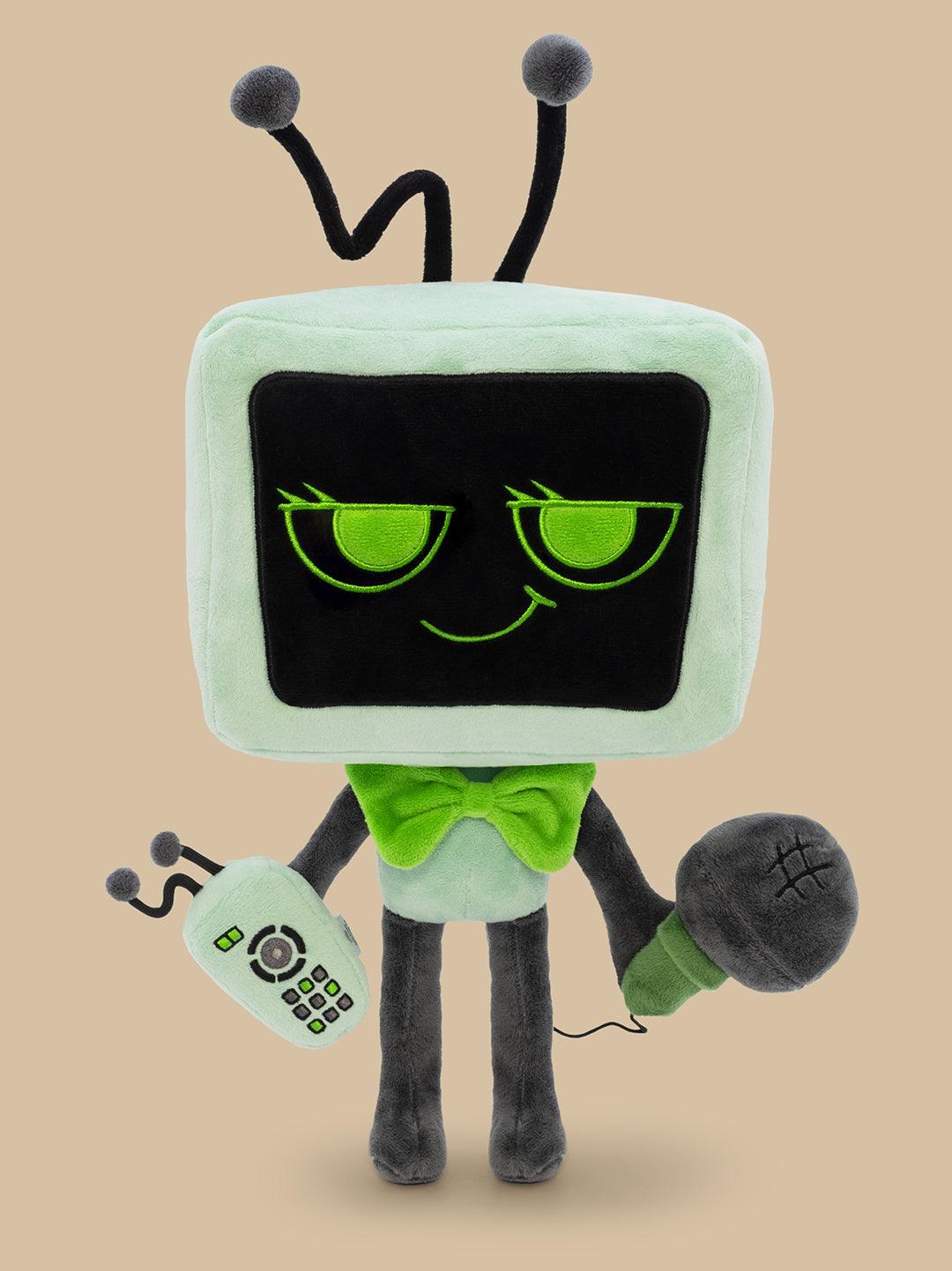 Plush toy resembling a vintage television set with a face, remote control, and microphone on a beige background.