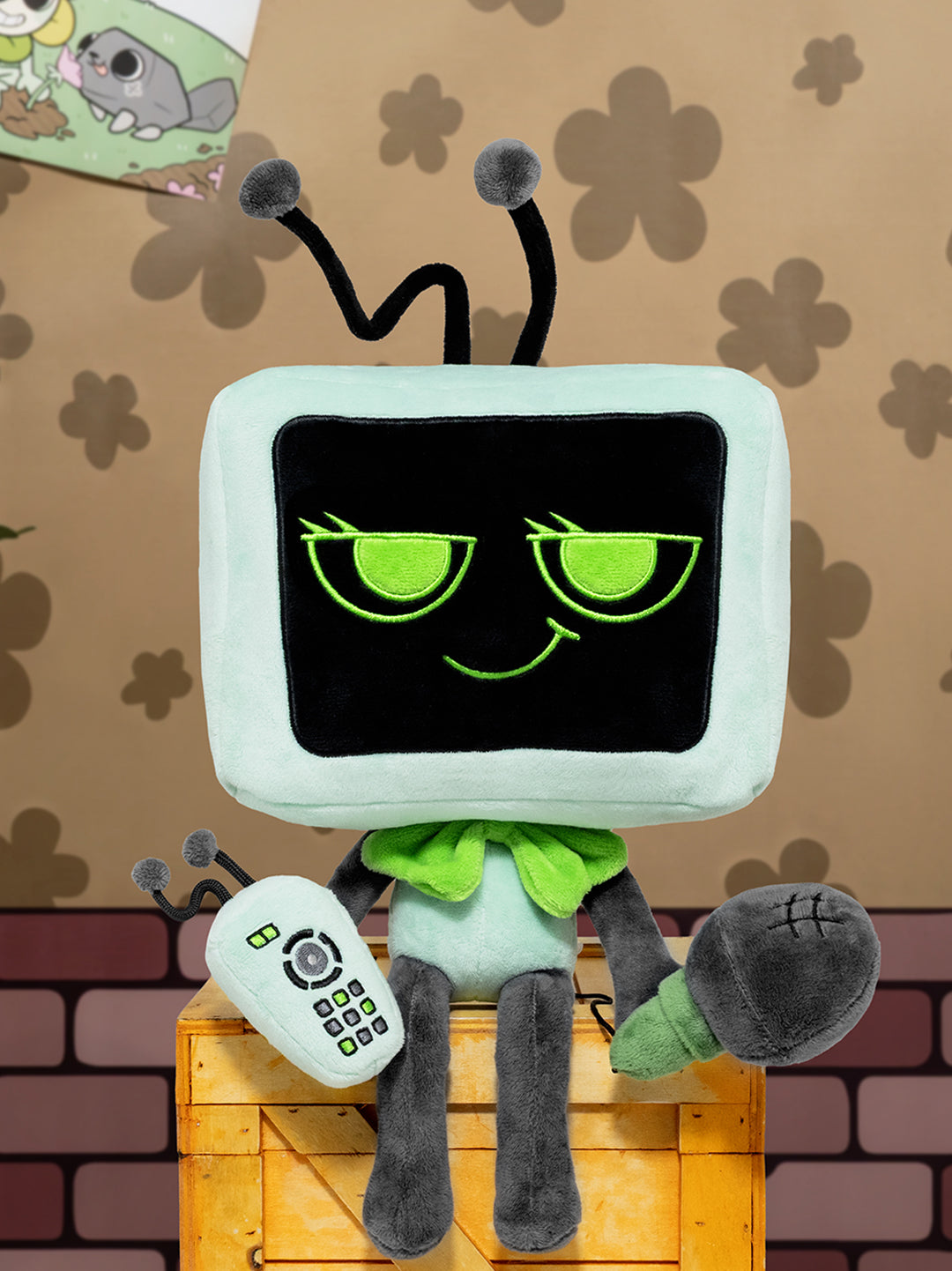 Toy resembling a television set with a face, sitting on a wooden crate against a patterned wall.