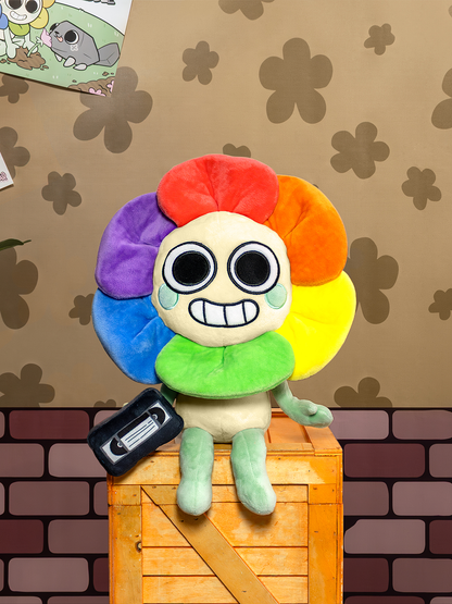 Colorful plush toy with a rainbow design on a wooden crate against a patterned wall.