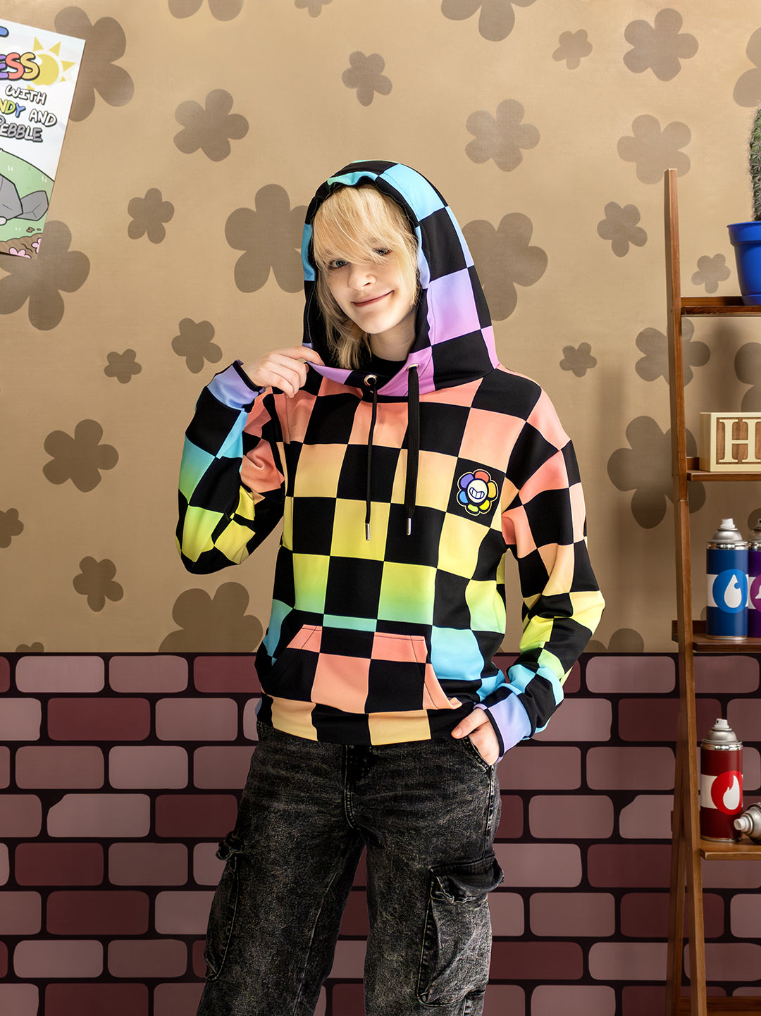 Person wearing a colorful checkered hoodie in front of a patterned wall.