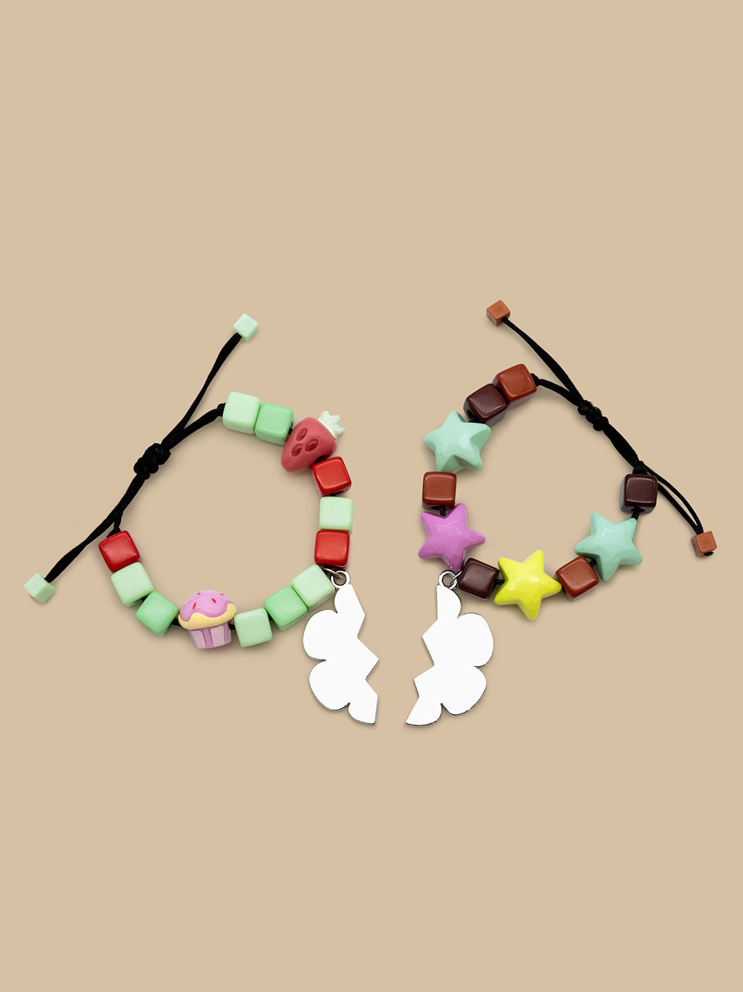 Two colorful beaded bracelets displayed side by side on a solid beige background. The left bracelet features mint green, red, and white beads with a small cupcake charm and white bunny charms.