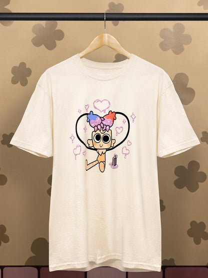 An off-white short-sleeve t-shirt hanging on a wooden hanger against a patterned brown wall. The shirt features a cartoon graphic of a character with colorful hair and sunglasses inside a heart outline.