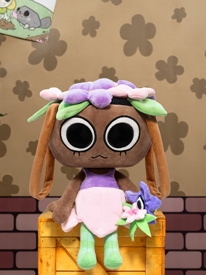 Plush toy with a brown face, purple dress, and green hair on a wooden block with a patterned background.