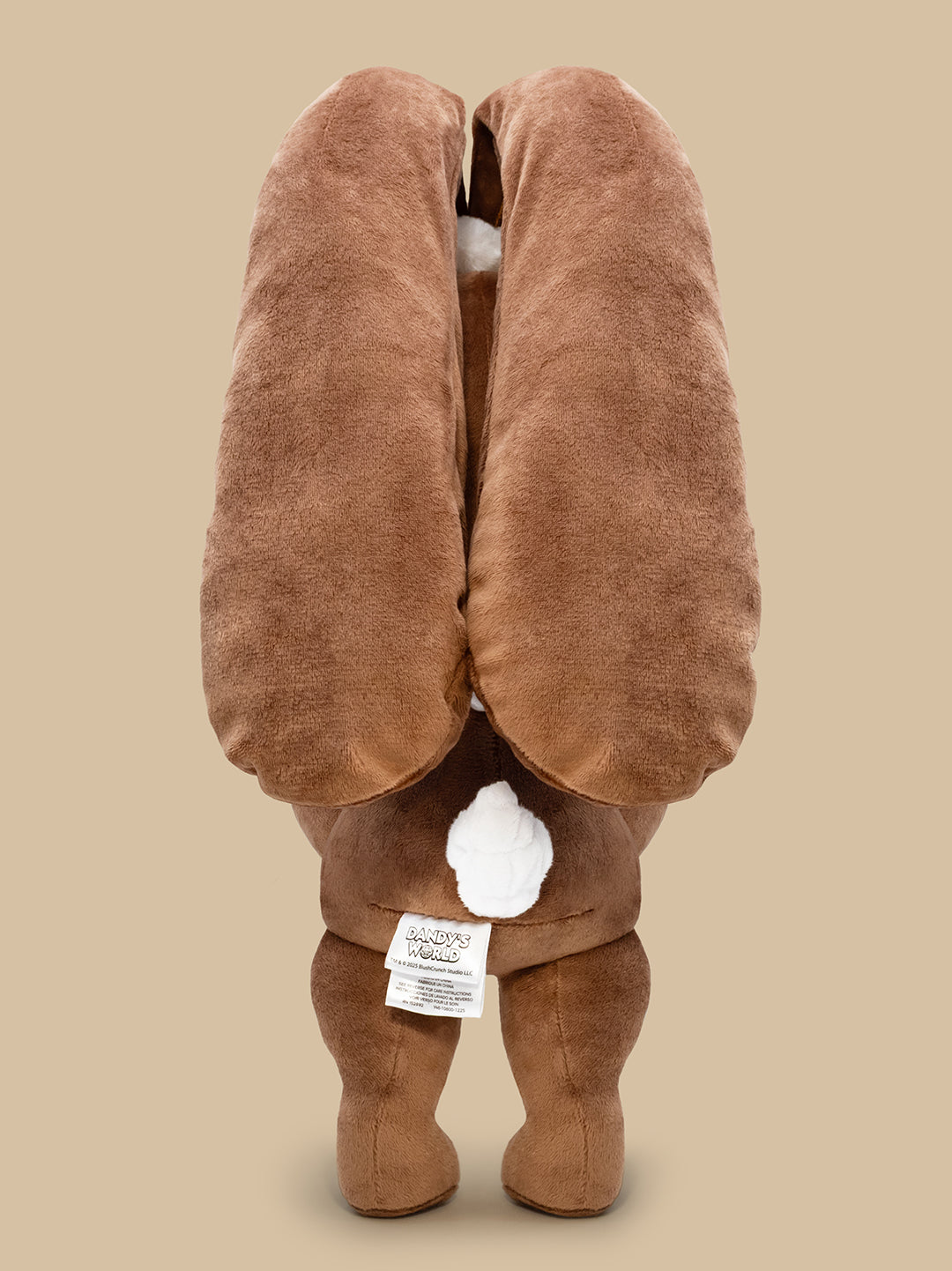 Brown plush toy with a tag on a beige background