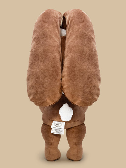 Brown plush toy with a tag on a beige background