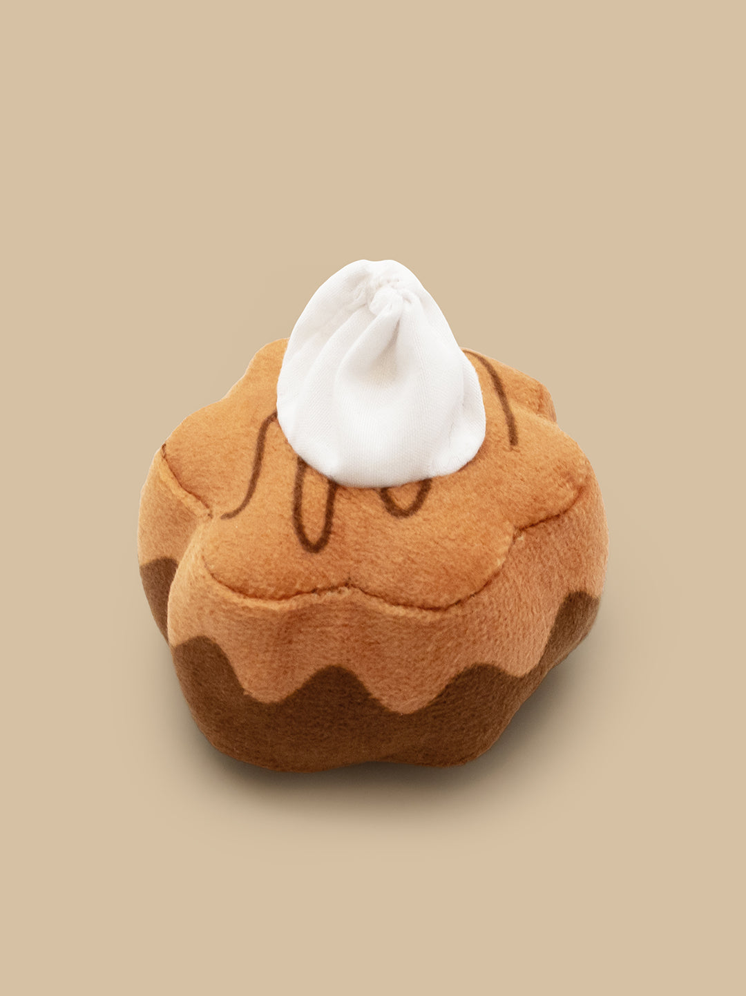 Plush toy shaped like a brownie with white cream on a beige background