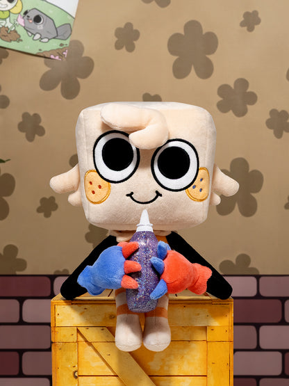 A plush toy character with a square beige head, large black eyes, and a black cape, sitting on a yellow crate and holding a purple glitter bottle with blue and orange hands. The background features a beige wall with brown flower patterns and a brick design at the bottom.