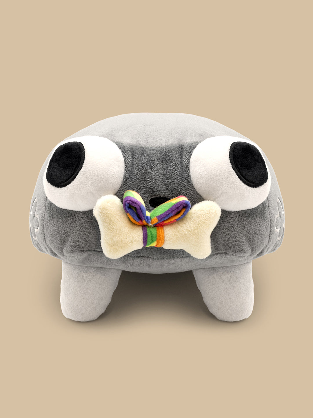 Gray plush toy with large eyes and a rainbow bone on a beige background