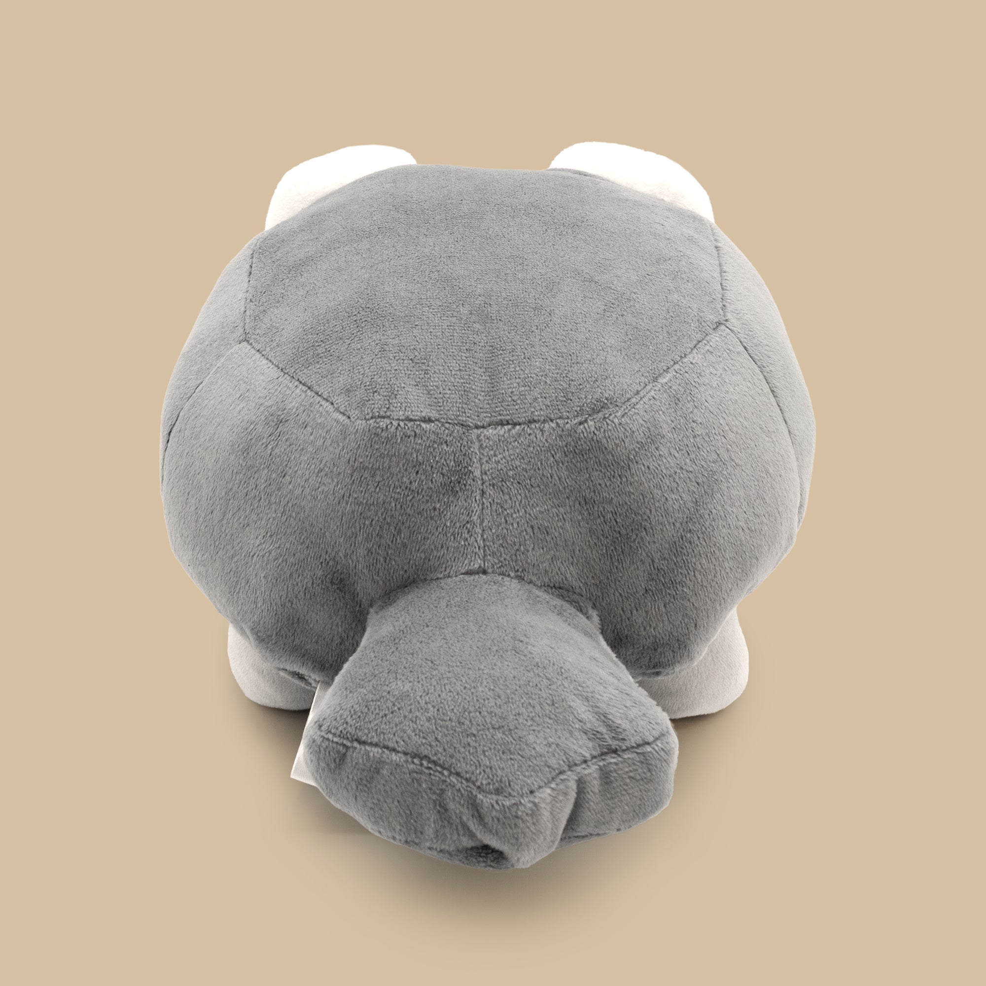 Gray plush toy resembling a turtle on a beige background