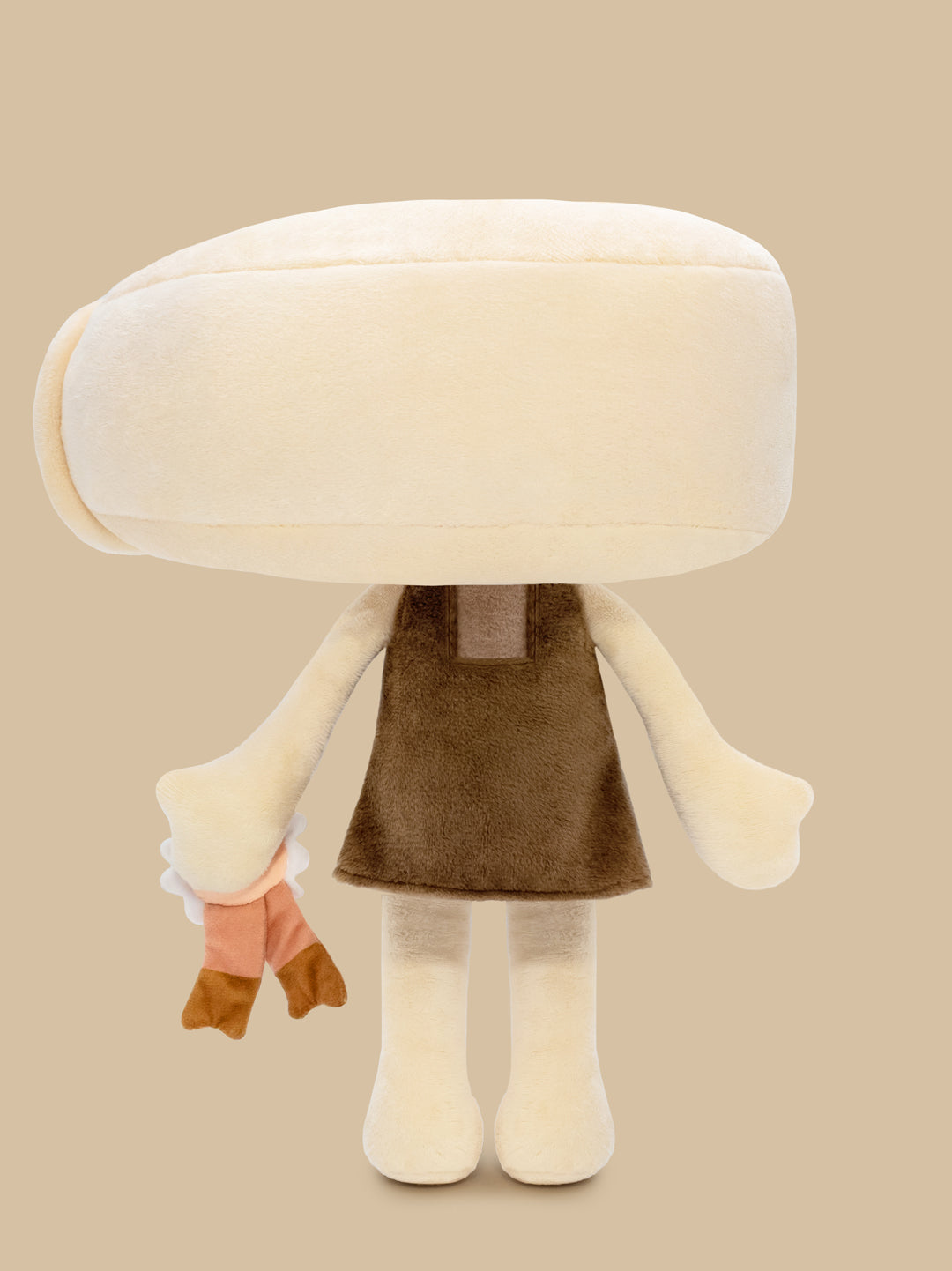 Plush toy with a large white head and brown dress on a beige background